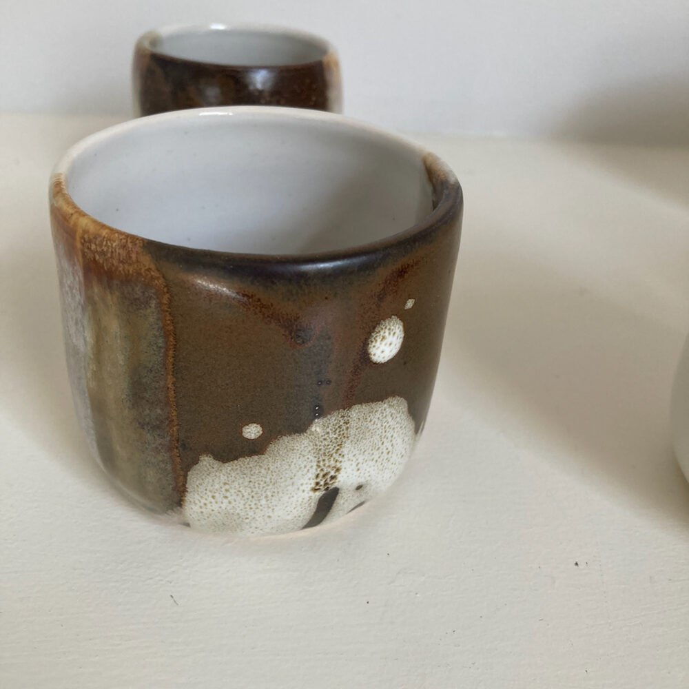 Handmade tumbler with dark brown glaze and a large cream circle, white interior