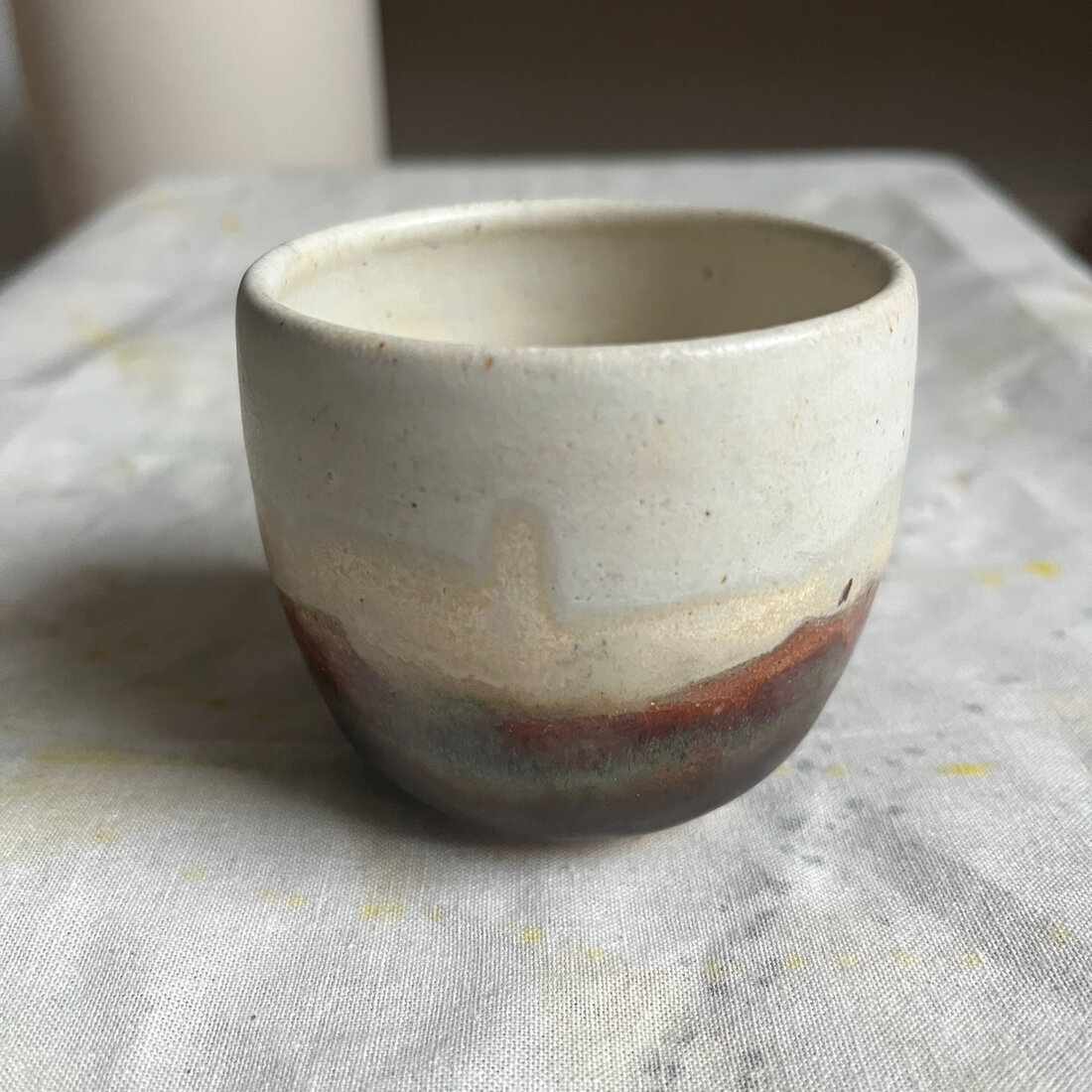 Handmade Landscape cappuccino cup with cream glaze breaking to a warm red-brown band at the base