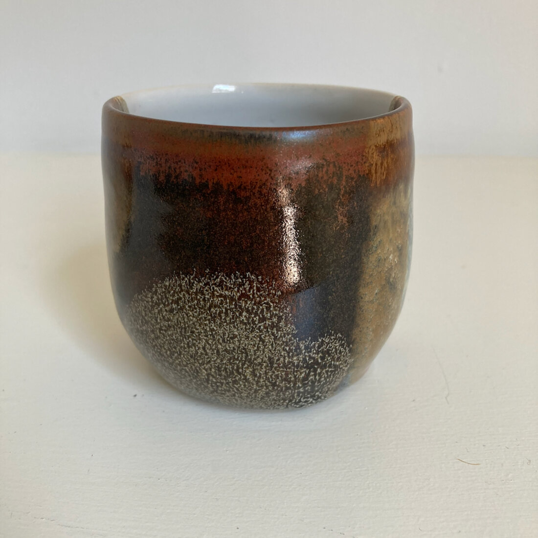 Large handmade cup with iron red glaze breaking to ash speckle, white interior