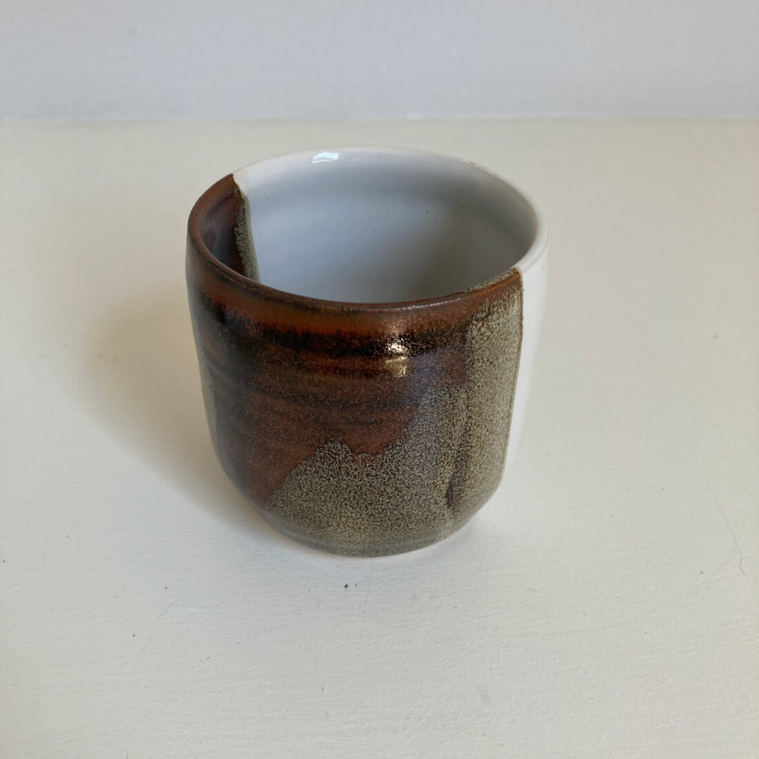Medium handmade cup with warm amber speckled glaze, white interior