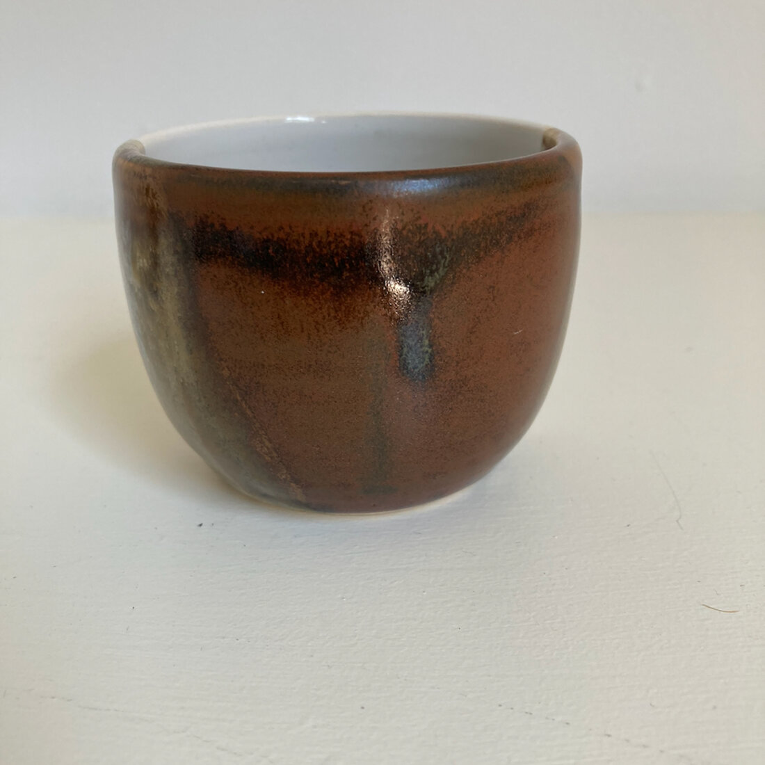 Medium handmade cup with rich burnt amber glaze, white interior