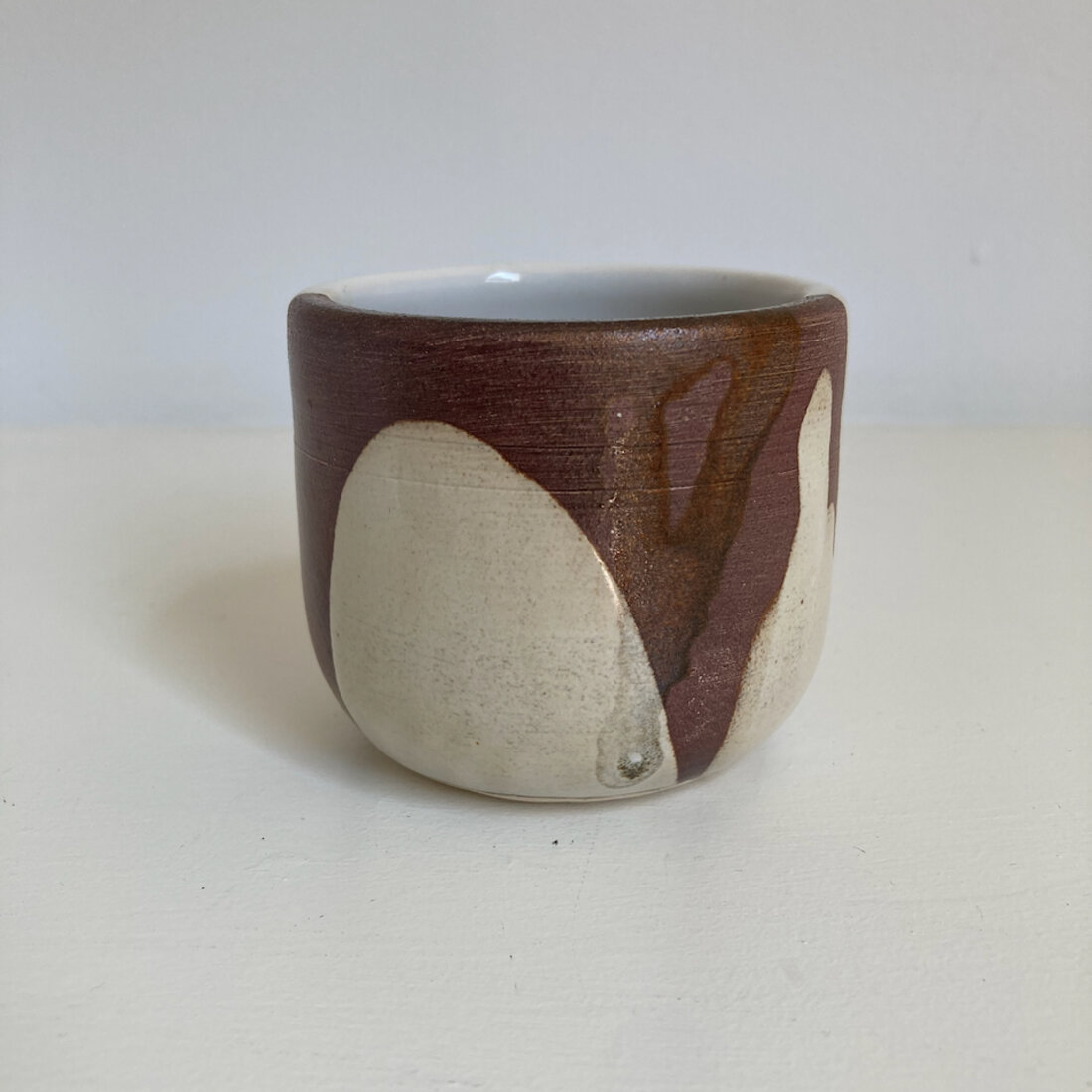 Medium handmade cup with ash grey speckled glaze and a dark iron rim, white interior