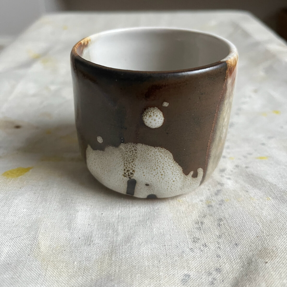 Handmade Moon cappuccino cup with dark iron glaze and a pale moon-like circle motif, white interior