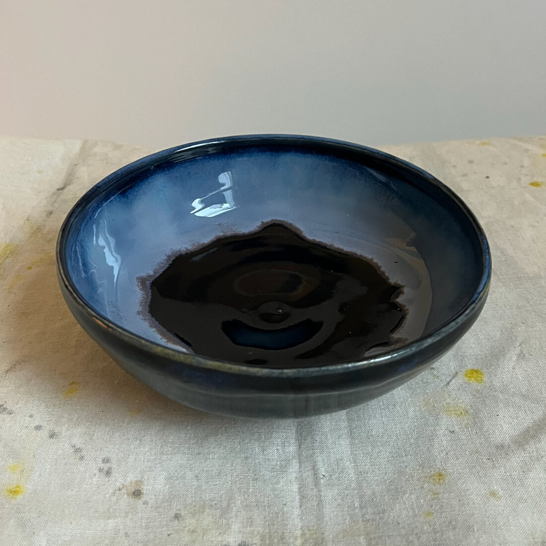 Handmade bowl with deep obsidian glaze and a pale blue flux band inside