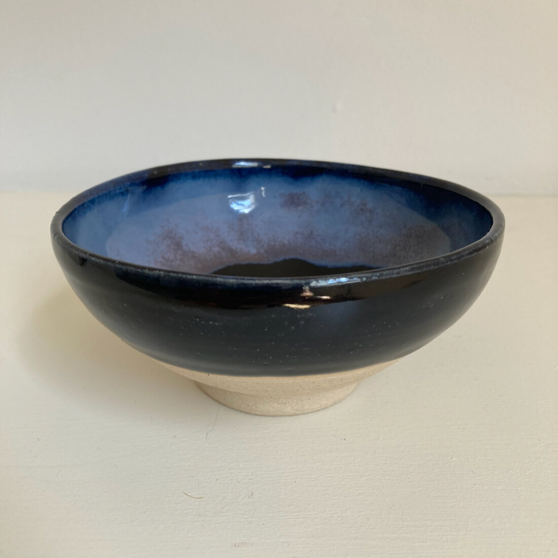 Small handmade bowl with deep cobalt-black glaze outside and pale blue-grey glaze inside