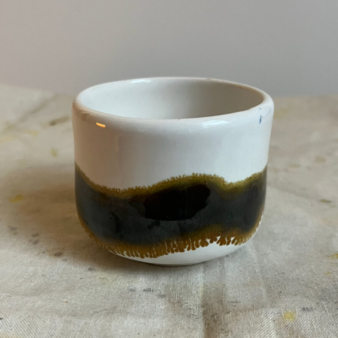 Handmade Tideline cappuccino cup, white glaze with a dark olive-black band and drippy edge